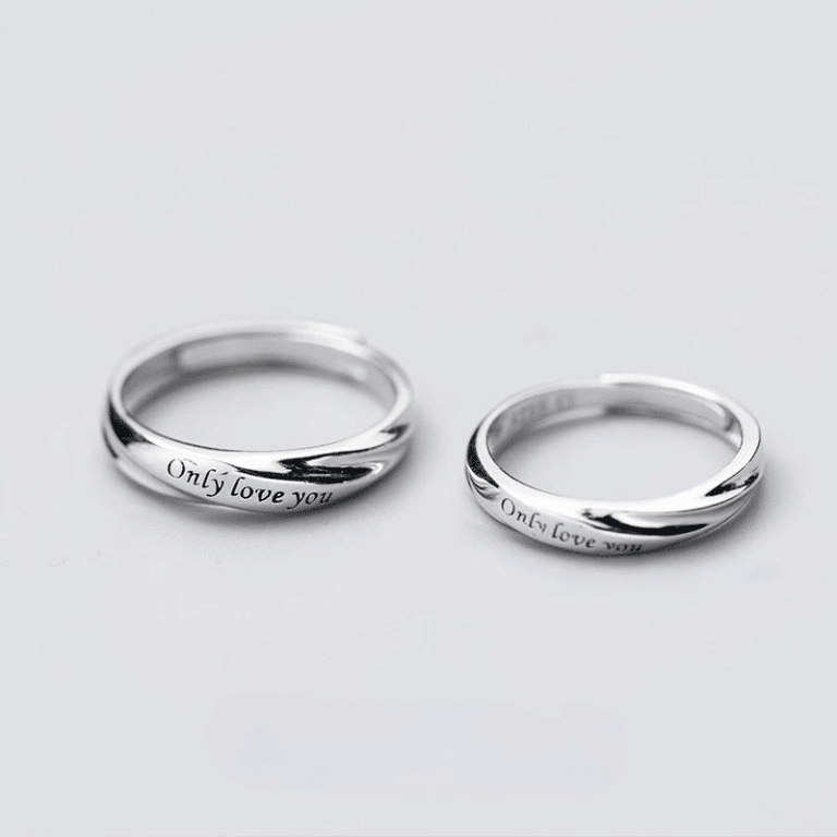 Ensemble de bagues avec lettres sculptées pour couple sur un fond blanc