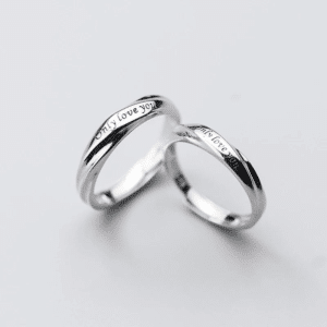 Ensemble de bagues avec lettres sculptées pour couple sur un fond blanc