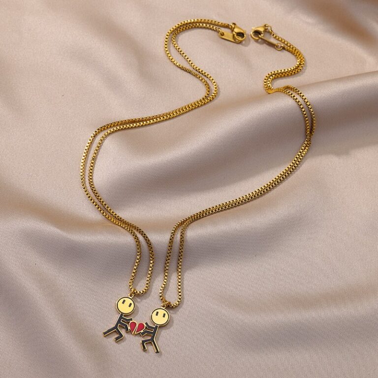 Des Colliers romantiques plaqué or pour couple sur un tissu en satin beige