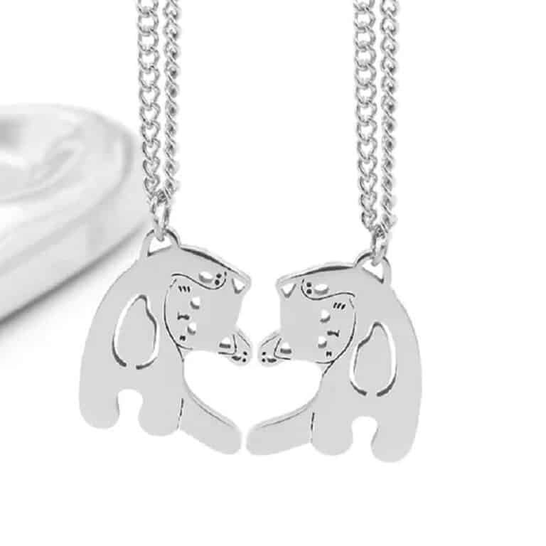 Des Colliers pour couple au design de chat formant un cœur sur un fond blanc